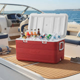 A red Sea-Breeze cooler filled with ice and assorted bottled drinks, placed on the deck of a boat with the ocean in the background.